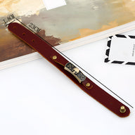 Bracelet en cuir marron avec motif tête de mort et os en métal doré.