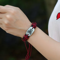Bracelet en cuir rouge avec plaque centrale argentée décorée d'une tête de mort noire, style ajustable.