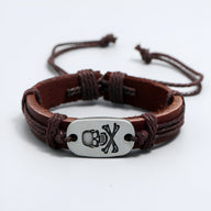 Bracelet en cuir marron pour homme avec plaque métal argentée gravée d'une tête de mort et os croisés.