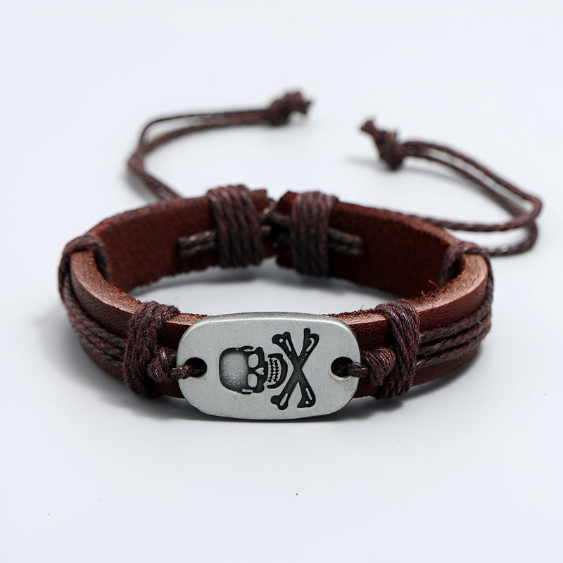 Bracelet en cuir marron pour homme avec plaque métal argentée gravée d'une tête de mort et os croisés.