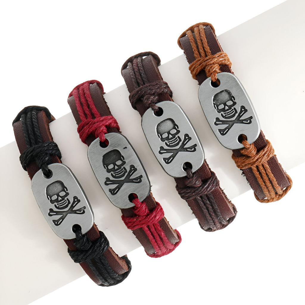 Bracelet en cuir noir avec plaque métal gris gravée d'une tête de mort et os croisés.