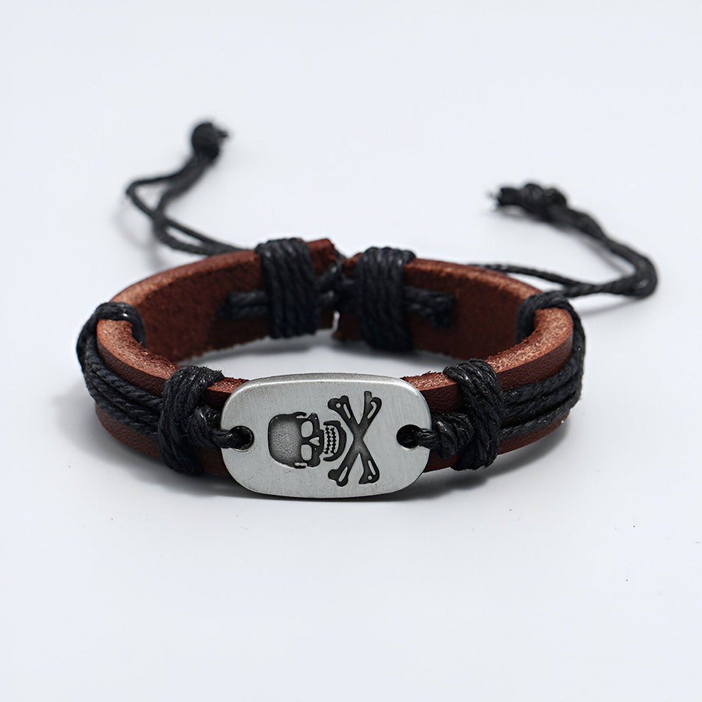 Bracelet en cuir marron avec cordons noirs et plaque métal tête de mort et os croisés.