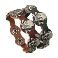 Deux bracelets en cuir noir et marron avec motifs têtes de mort en métal argenté, fermeture à pression.