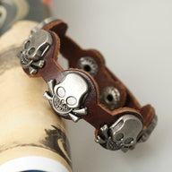 Bracelet en cuir marron avec trois têtes de mort en métal argenté pour homme.