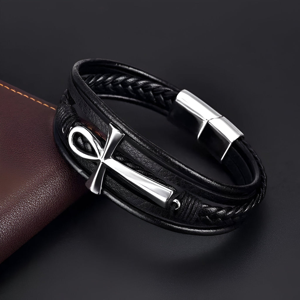 Bracelet en cuir noir multi-rangs avec croix ankh argentée et fermoir métallique brillant.