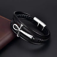 Bracelet en cuir noir multi-rangs avec croix ankh argentée et fermoir métallique brillant.