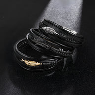Bracelet multi-rangs en cuir noir avec motif plume en métal doré et argenté, style masculin contemporain.