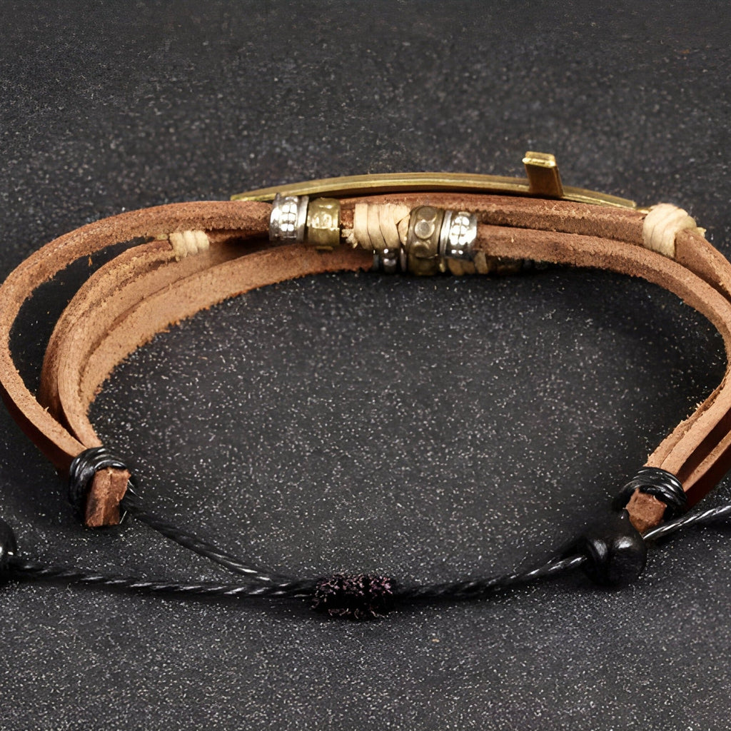 Bracelet homme multi-rangs en cuir marron avec charm grande croix métal doré et fermoir ajustable noir.