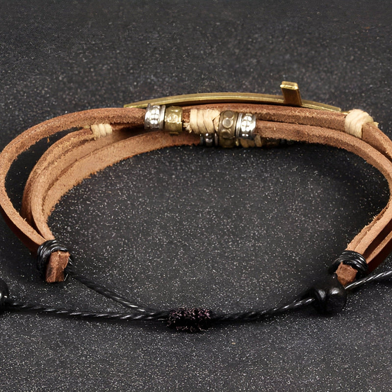 Bracelet homme multi-rangs en cuir marron avec charm grande croix métal doré et fermoir ajustable noir.