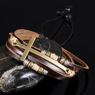 Bracelet homme multi-rangs en cuir marron avec charm grande croix dorée et détails en corde beige et métal argenté.