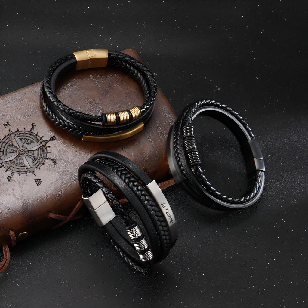 Bracelet multi-rangs en cuir noir avec fermoir doré, style tressé et détails métalliques argentés et noirs.