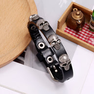 Bracelet en cuir noir avec plusieurs têtes de mort métalliques et boucle argentée.