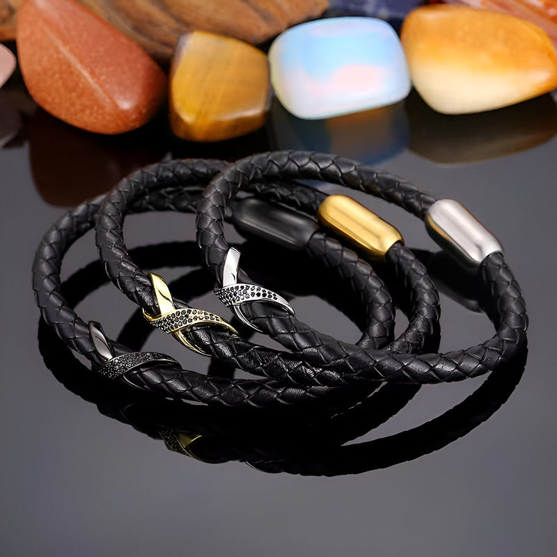 Bracelet en cuir noir tressé avec nœud central en acier doré et argenté, fermoir magnétique assorti.