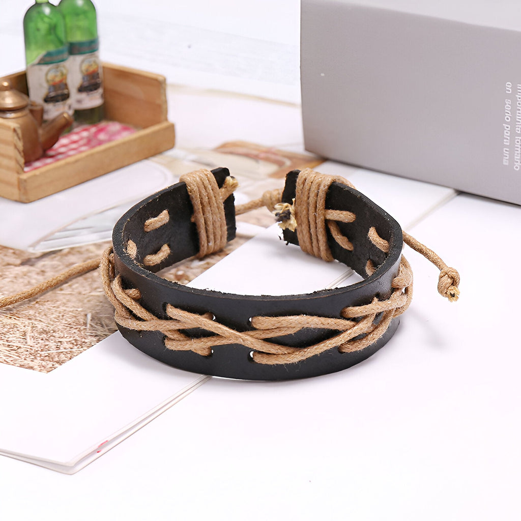 Bracelet en cuir noir avec fils beige entrelacés et fermoir coulissant réglable.
