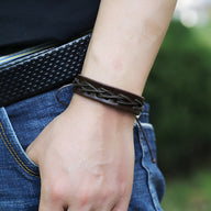 Bracelet en cuir café avec fils entrelacés, style masculin, porté au poignet.
