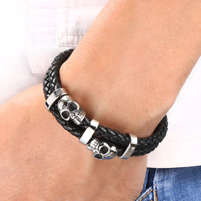 Bracelet en cuir noir tressé avec ornement double têtes de mort en métal argenté.