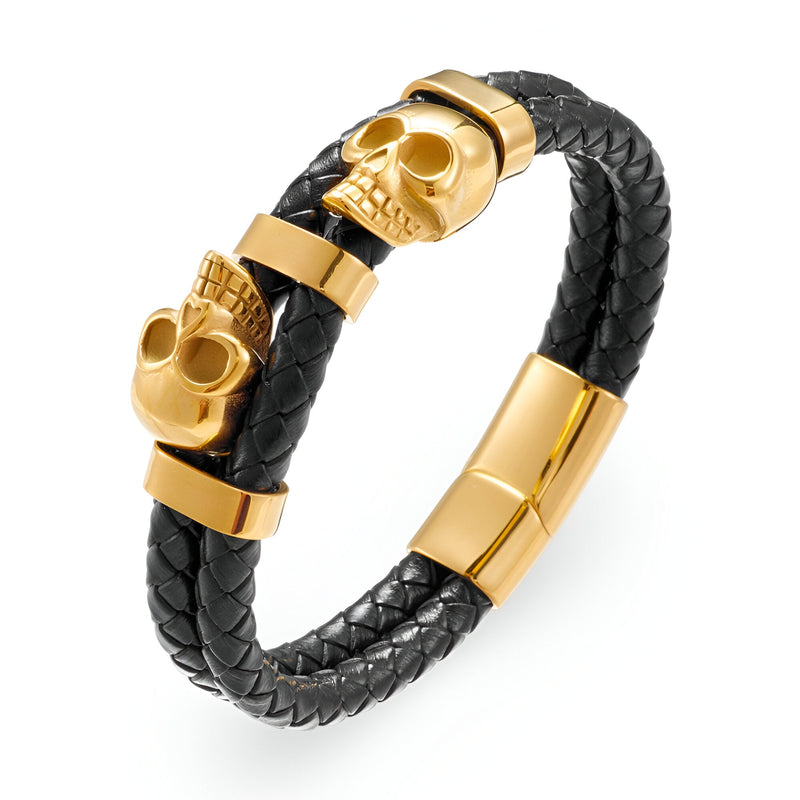 Bracelet en cuir noir tressé avec ornement double têtes de mort dorées et fermoir doré magnétique.