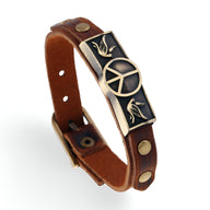 Bracelet en cuir marron avec plaque métallique ornée d’un symbole peace et d’oiseaux, style unisexe.