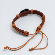 Bracelet en cuir marron avec cordons tressés orange et fermoir noir ajustable.