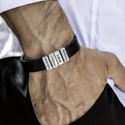 Bracelet en cuir noir avec deux plaques métalliques gravées "Patience" et "Love" porté au poignet.