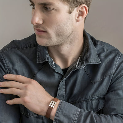 Bracelet en cuir noir avec quatre plaques métalliques rectangulaires, style moderne et masculin.