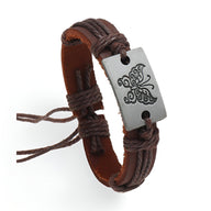 Bracelet en cuir café avec plaque rectangulaire argentée ornée d’un motif papillon gravé.