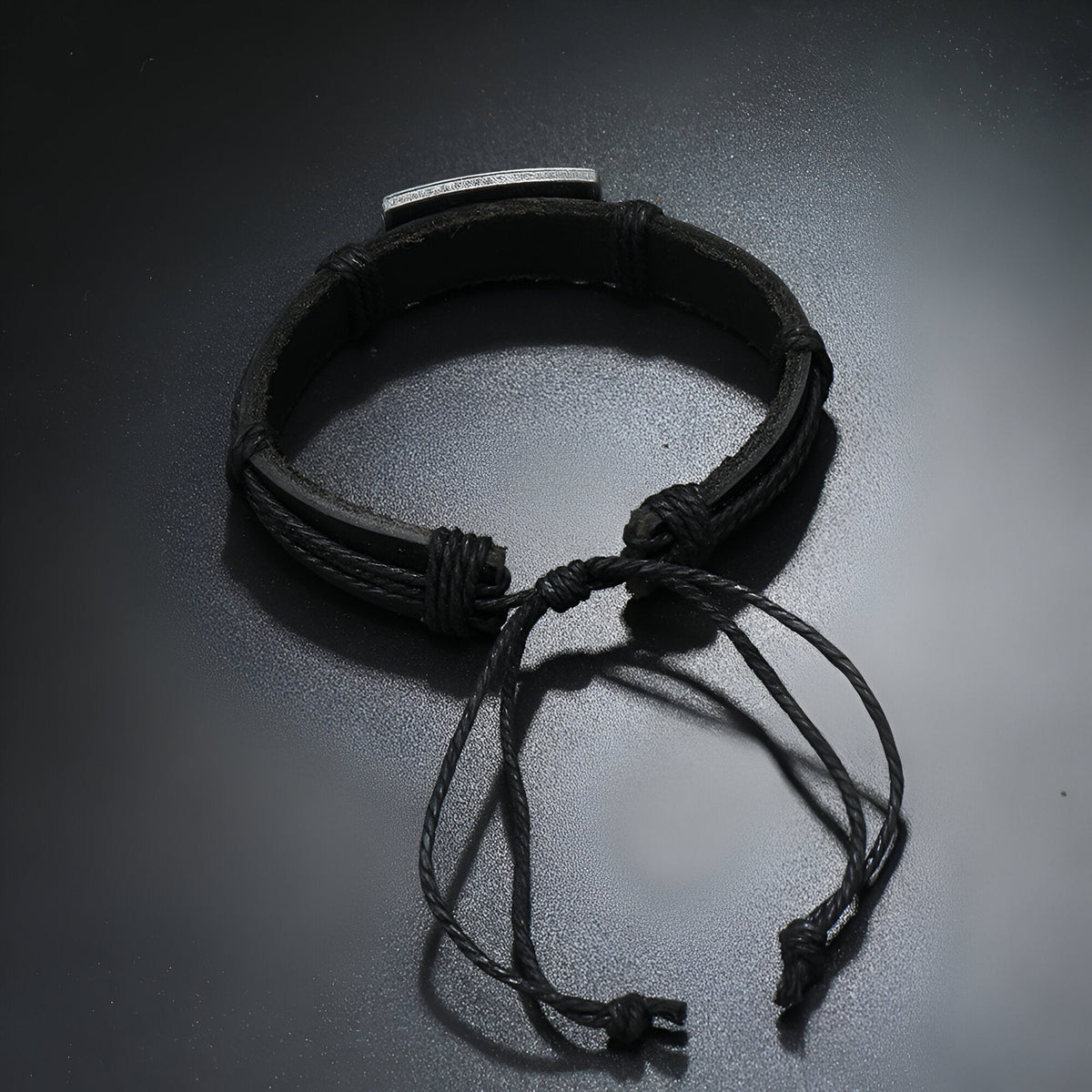 Bracelet en cuir noir ajustable avec plaque métallique gravée d’un motif papillon.