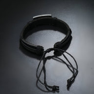 Bracelet en cuir noir ajustable avec plaque métallique gravée d’un motif papillon.