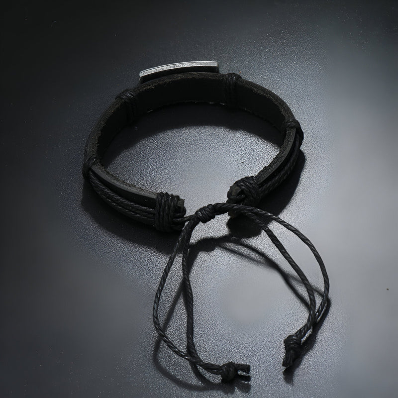 Bracelet en cuir noir ajustable avec plaque métallique gravée d’un motif papillon.