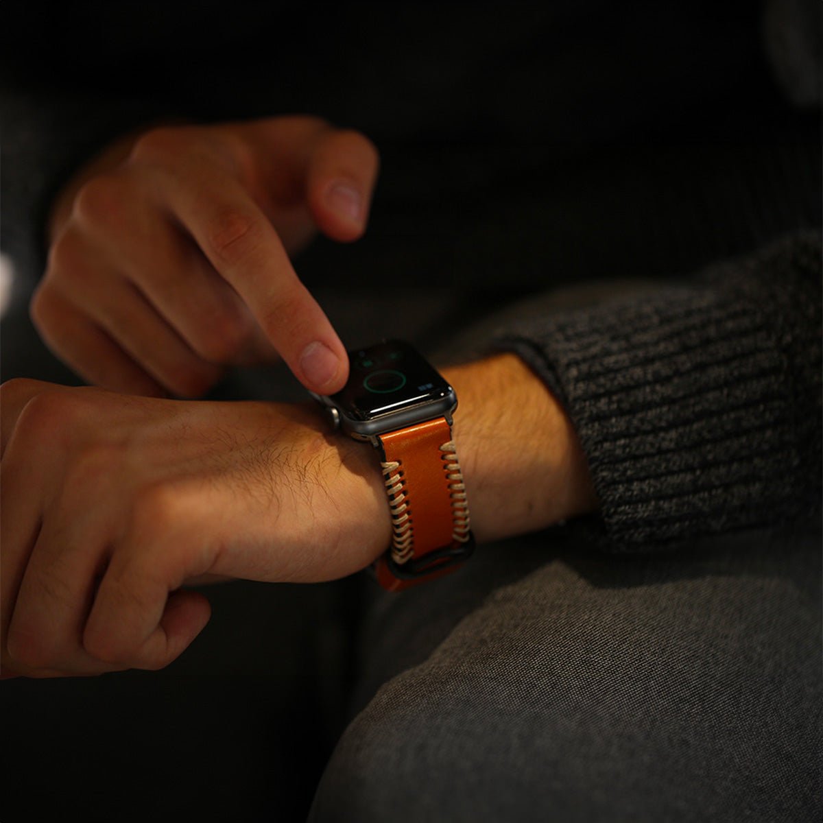 Bracelet en cuir orange à coutures blanches contrastées, boucle acier pour Apple Watch noire, style moderne et masculin.