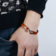 Bracelet en cuir cognac pour homme avec fermeture à crochet argenté, style minimaliste romain.
