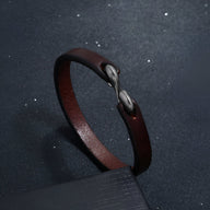 Bracelet en cuir marron foncé avec fermeture crochet simple en métal argenté, style masculin et minimaliste.