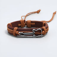 Bracelet en cuir marron foncé avec cordons tressés et charm guitare en métal argenté.
