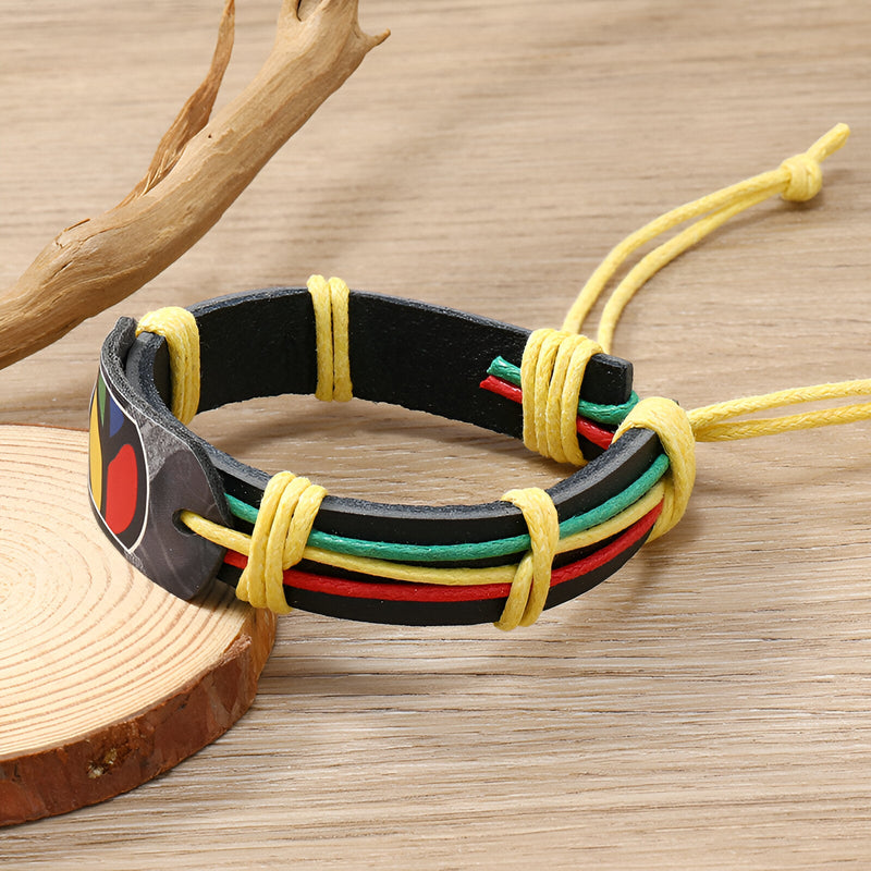 Bracelet en cuir noir avec fils rouges, verts et jaunes, style jamaïcain, ajustable avec cordons jaunes.