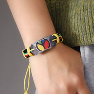 Bracelet en cuir noir homme avec plaque métal colorée motif style jamaïcain et cordon jaune réglable.