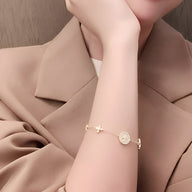 Bracelet en cuivre plaqué or avec pendentifs trèfle à 4 feuilles et pièce gravée, chaîne fine.