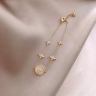 Bracelet fin en cuivre plaqué or avec trèfles à 4 feuilles et cercle orné de strass, fermoir ajustable.