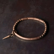 Bracelet en cuivre marron avec pendentif conique et perles rondes, style raffiné et minimaliste.