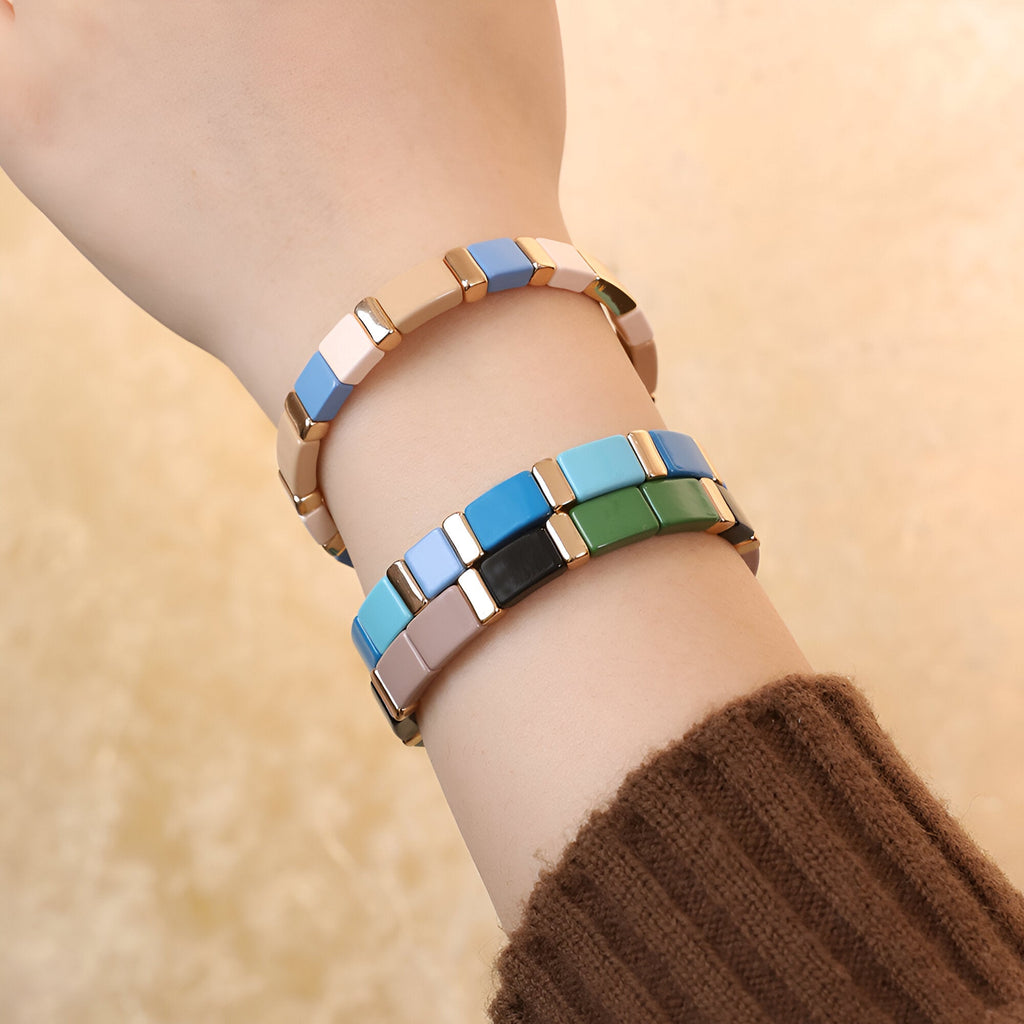 Bracelet émail coloré multicolore aux tons bleu, vert et beige sur poignet féminin.