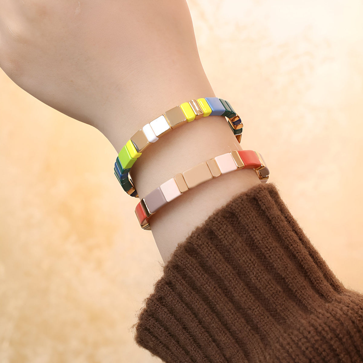 Bracelets en émail multicolores aux perles carrées, style contemporain, porté au poignet féminin.