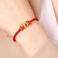 Bracelet rouge en fil ciré avec serpent doré enroulé, style minimaliste élégant.
