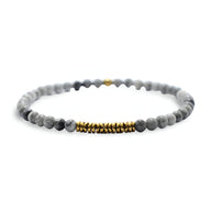 Bracelet fin pour homme en hématite et pierres naturelles gris clair avec perles dorées centrales.