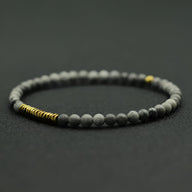 Bracelet fin pour homme en perles rondes grises mates avec petits anneaux dorés en hématite.