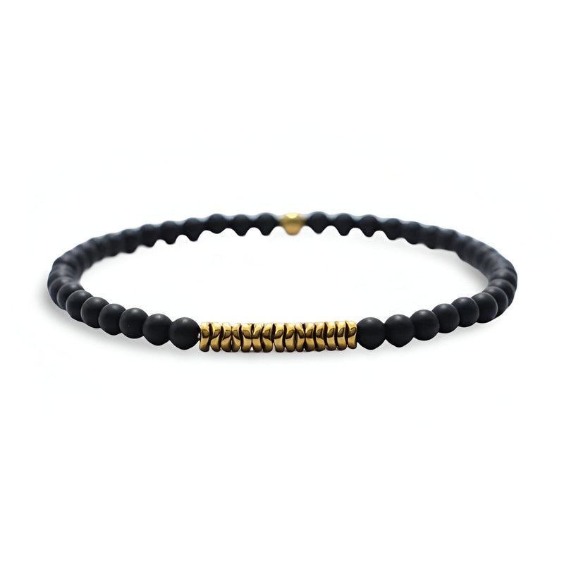Bracelet fin pour homme en perles noires mates avec détails cylindriques dorés et petit cœur doré.