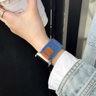 Bracelet en jean bleu avec étiquette cuir marron pour Apple Watch, style casual et ajustable.