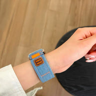 Bracelet en jean bleu clair ajustable avec détail de cuir marron pour Apple Watch.