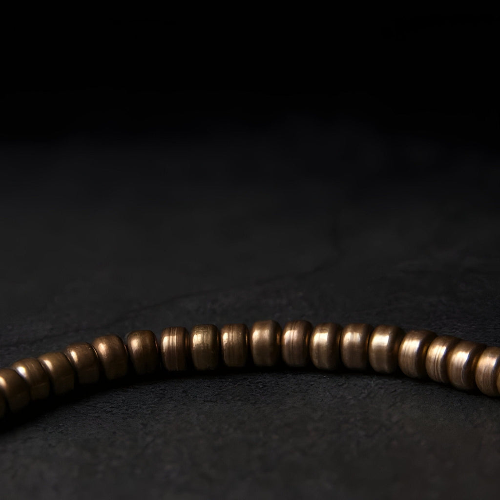 Bracelet femme en laiton marron avec petites perles cylindriques lisses, style minimaliste.