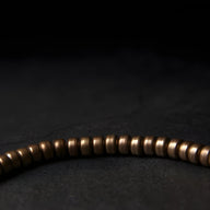 Bracelet femme en laiton marron avec petites perles cylindriques lisses, style minimaliste.