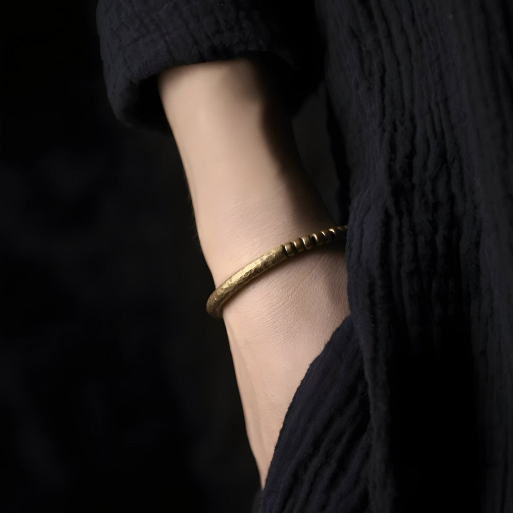 Bracelet en laiton doré à petites perles fines, style minimaliste, porté au poignet féminin.