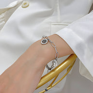 Bracelet en maille épaisse argentée avec pendentif arbre de vie sur poignet féminin.